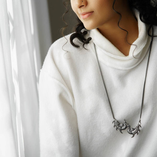 a woman wearing a white sweater and a necklace