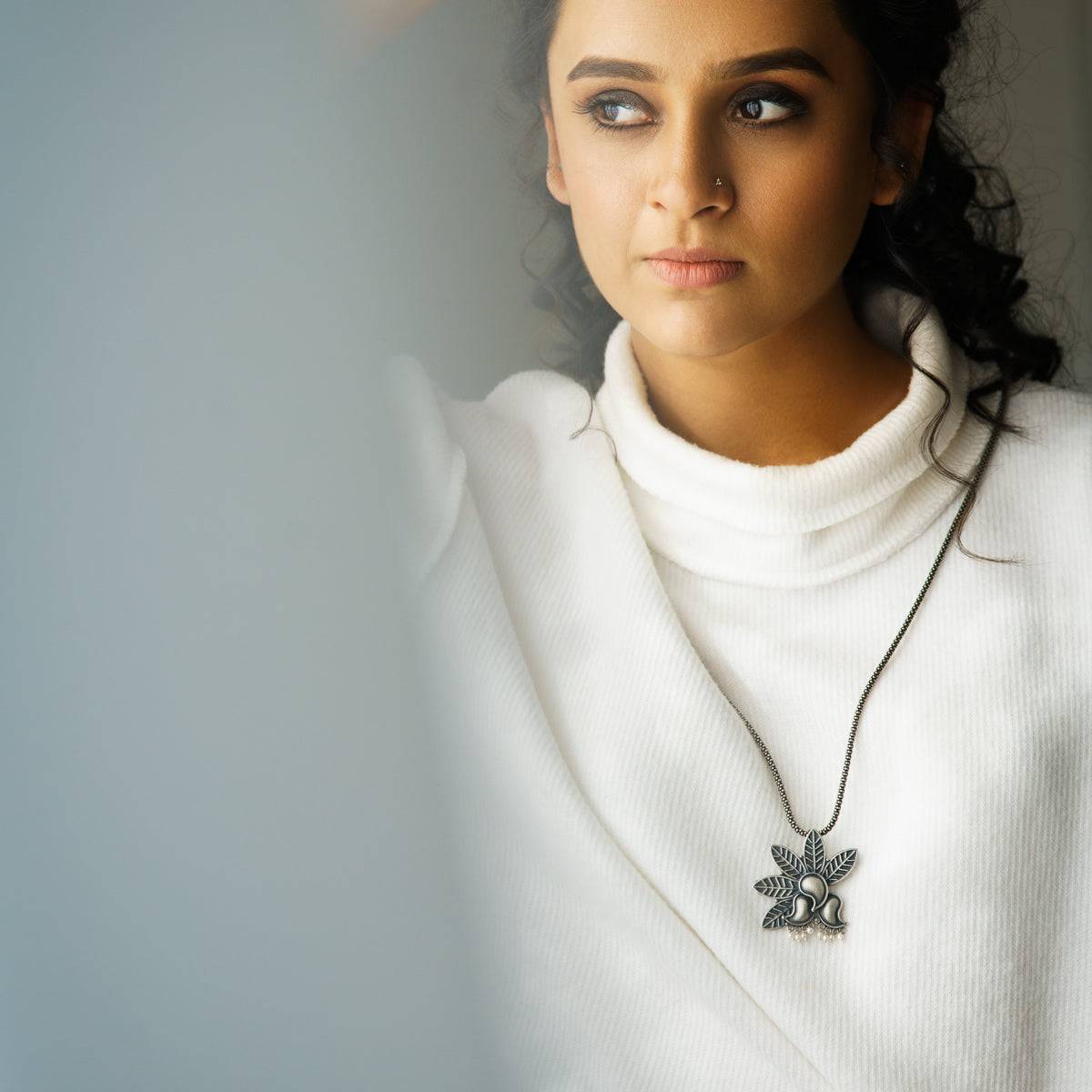 a woman wearing a white sweater and a necklace