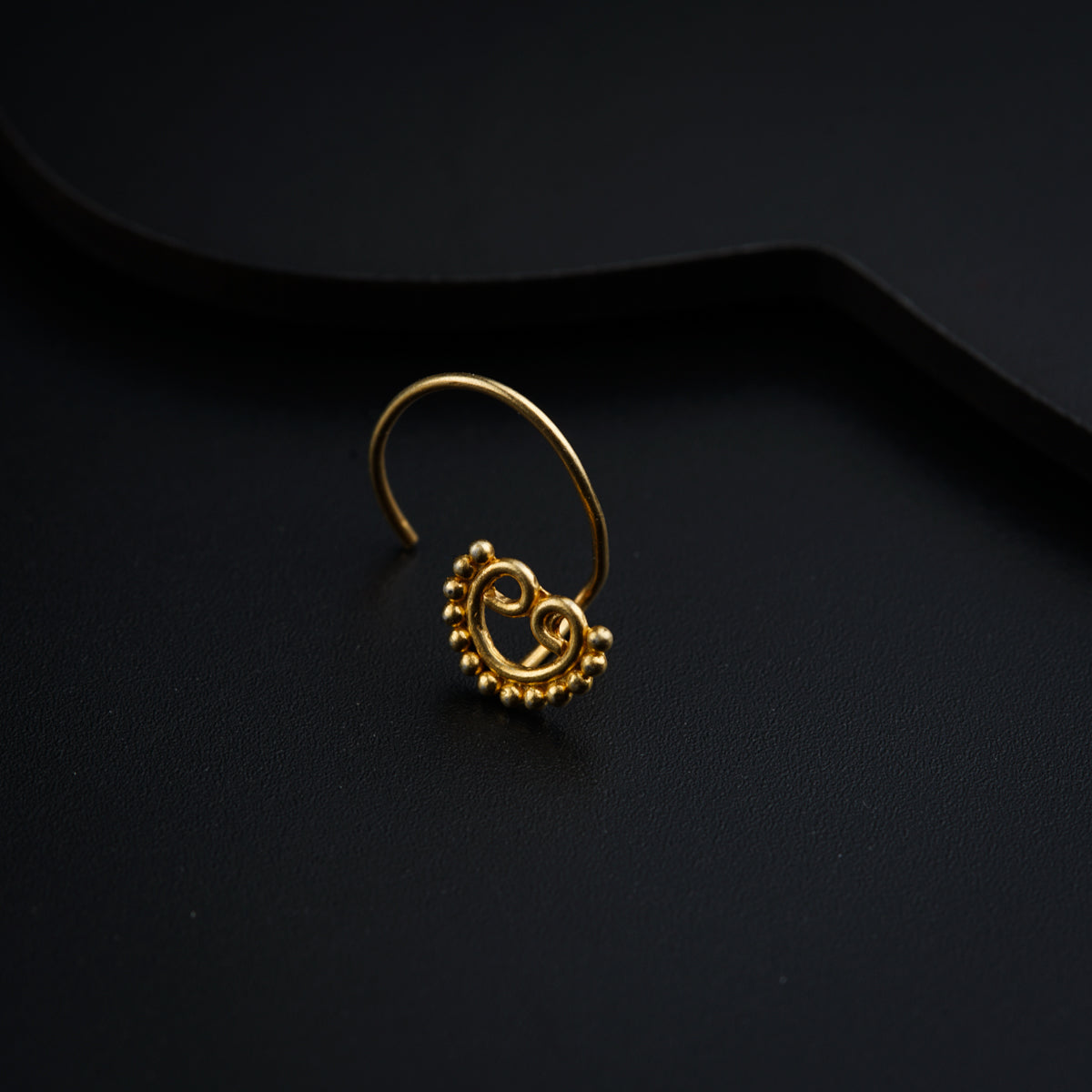 a gold nose ring on a black surface