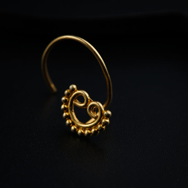 a gold nose ring on a black surface