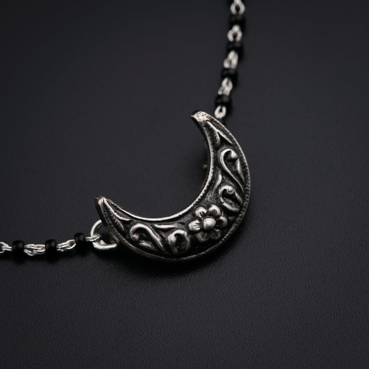 a necklace with a crescent design on a black background