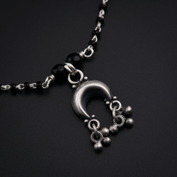 a black and silver necklace on a black surface