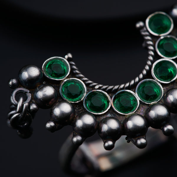 a close up of a ring with green stones