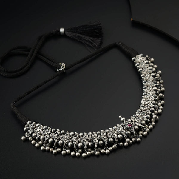 a necklace with beads and tassels on a black surface