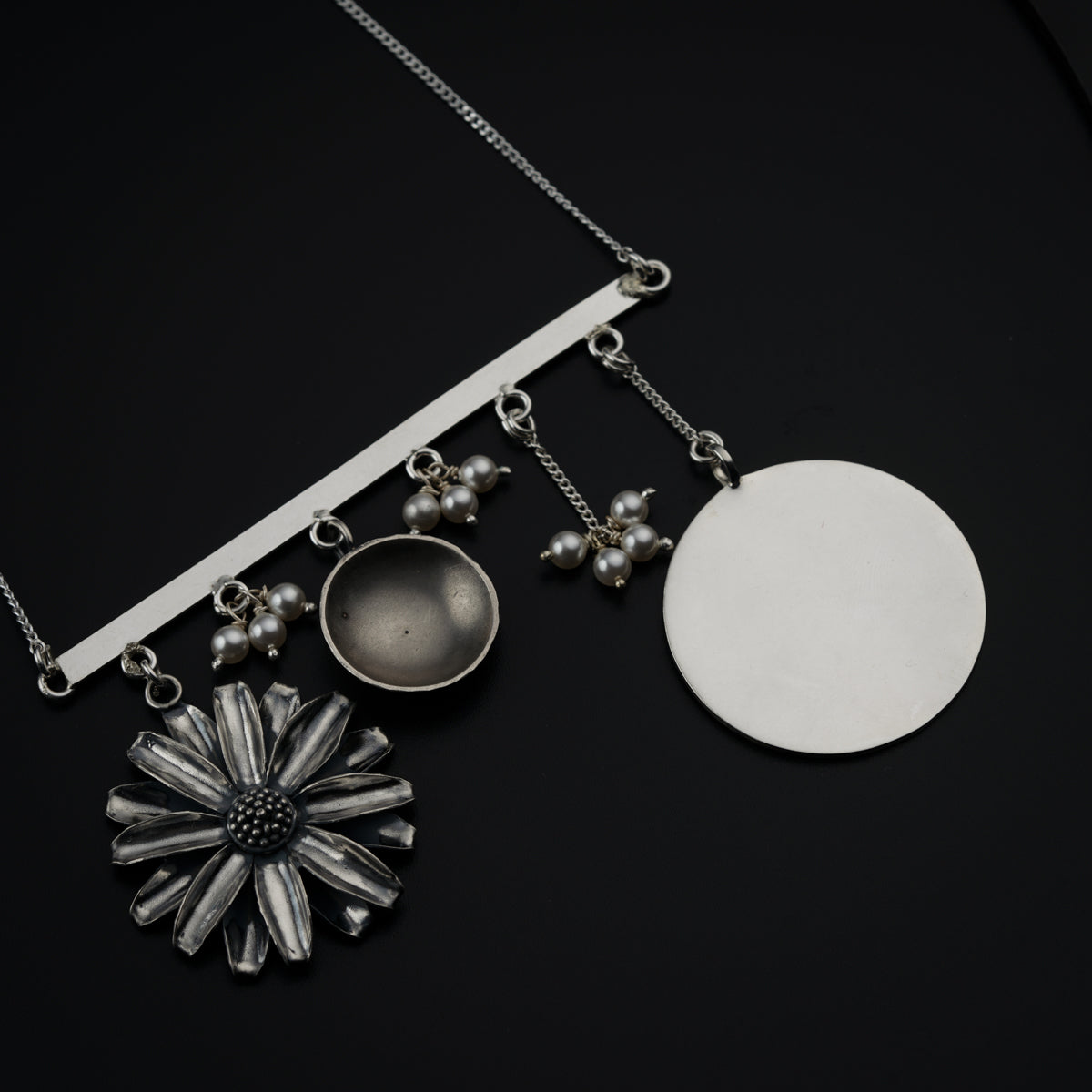 a necklace with a flower and a disc attached to it