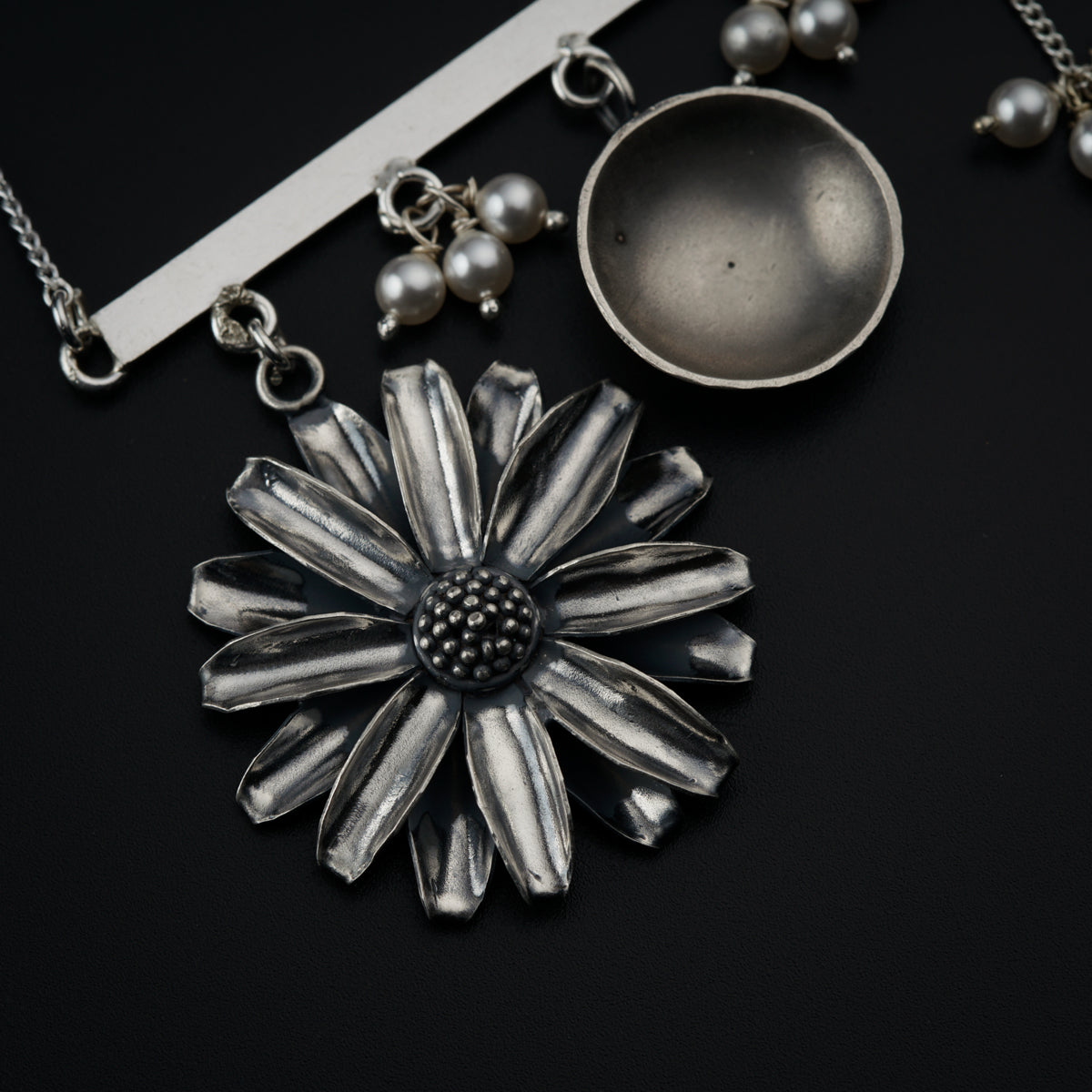 a silver necklace with a flower and pearls