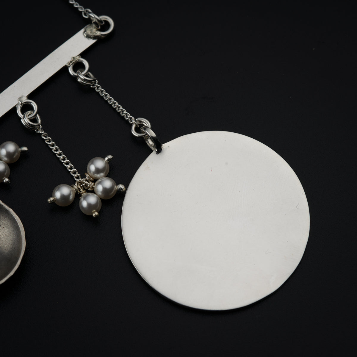 a silver spoon and a white disc on a black surface