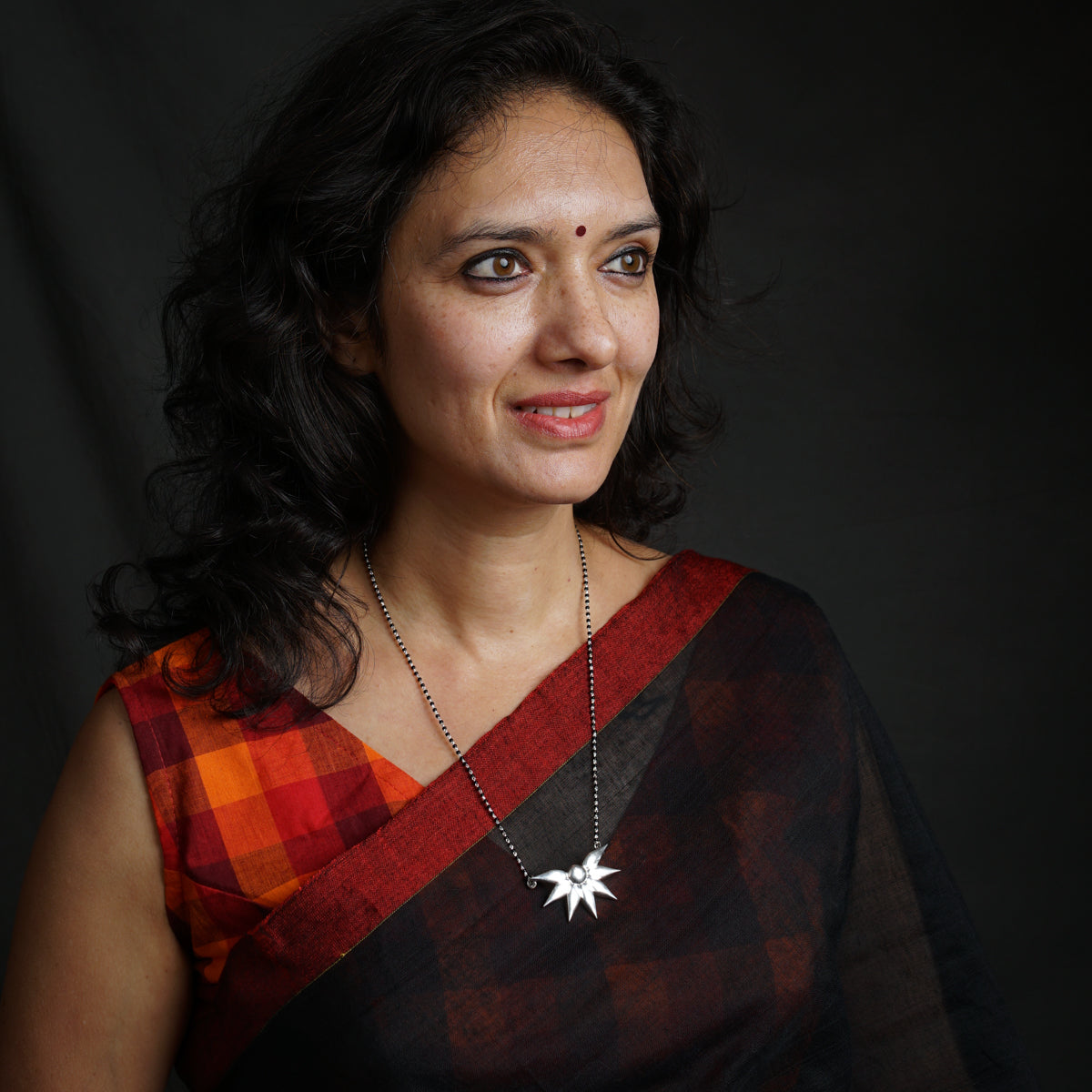a woman in a black and red sari posing for a picture