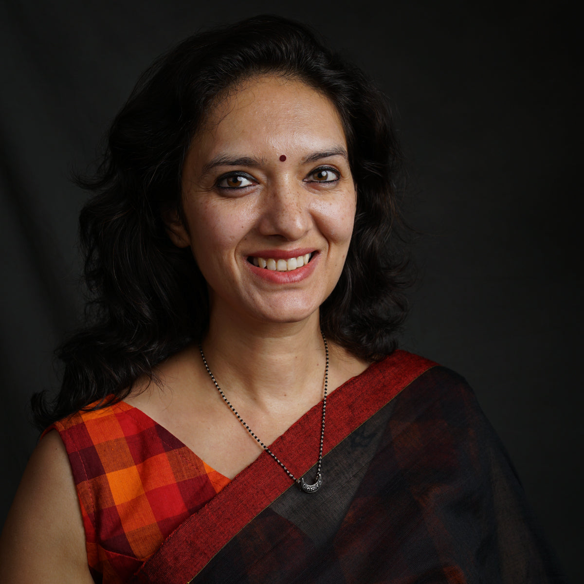 a woman in a red and black sari smiling