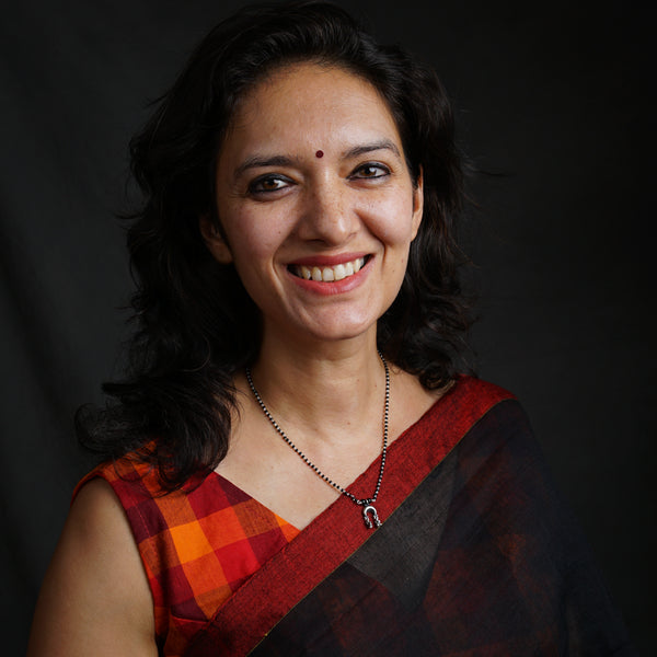 a woman in a red and black sari smiling