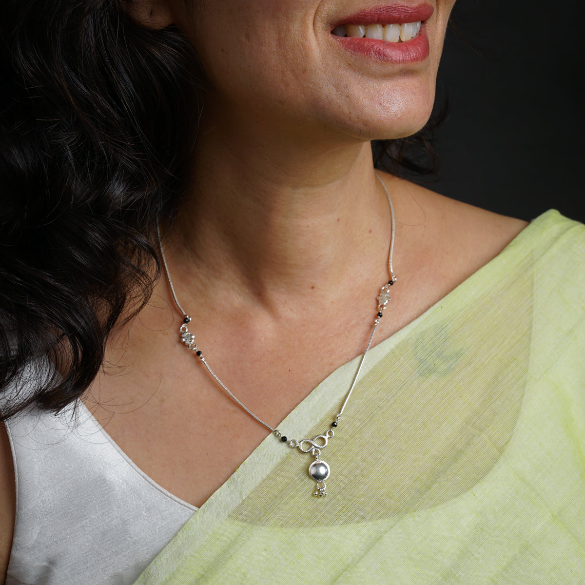 a woman wearing a necklace with a diamond on it