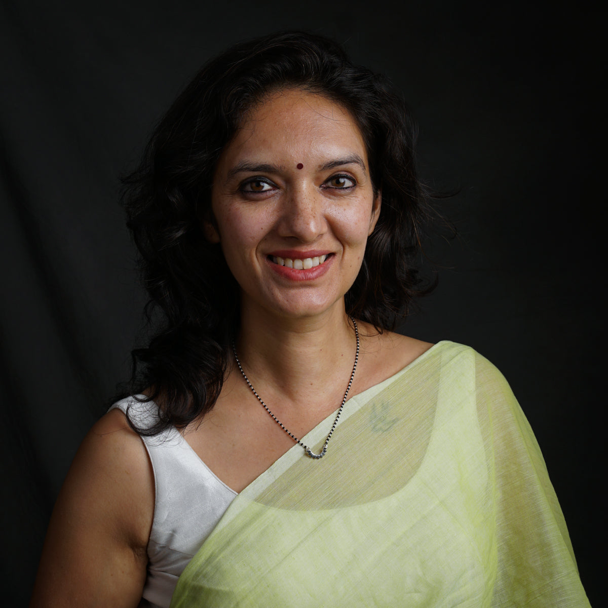 a woman in a green sari smiling for the camera
