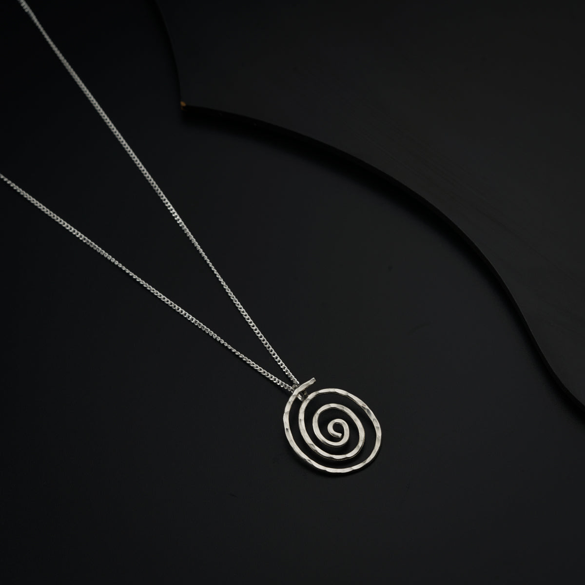 a silver necklace with a spiral design on it