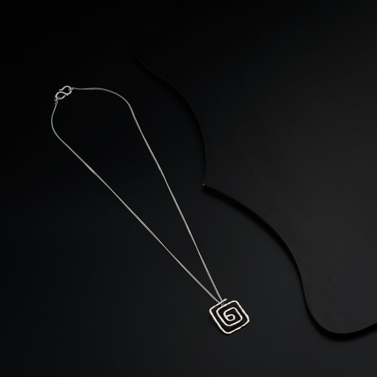 a black and white photo of a necklace on a black background
