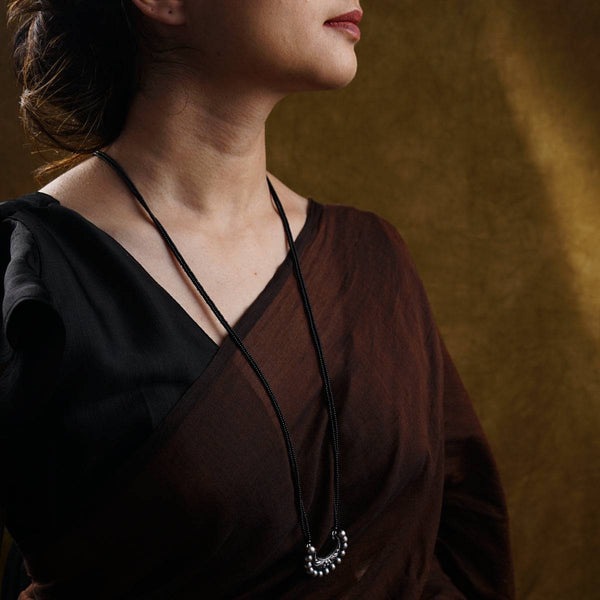 a woman wearing a brown shirt and a black necklace