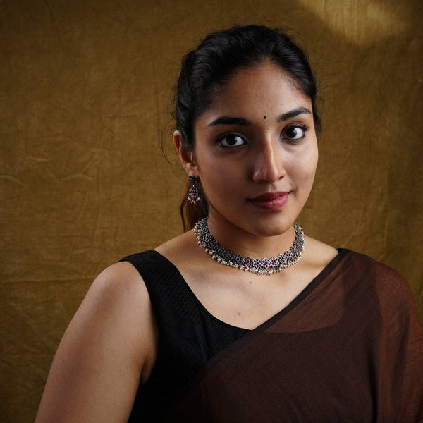 a woman in a brown dress with a necklace on her neck