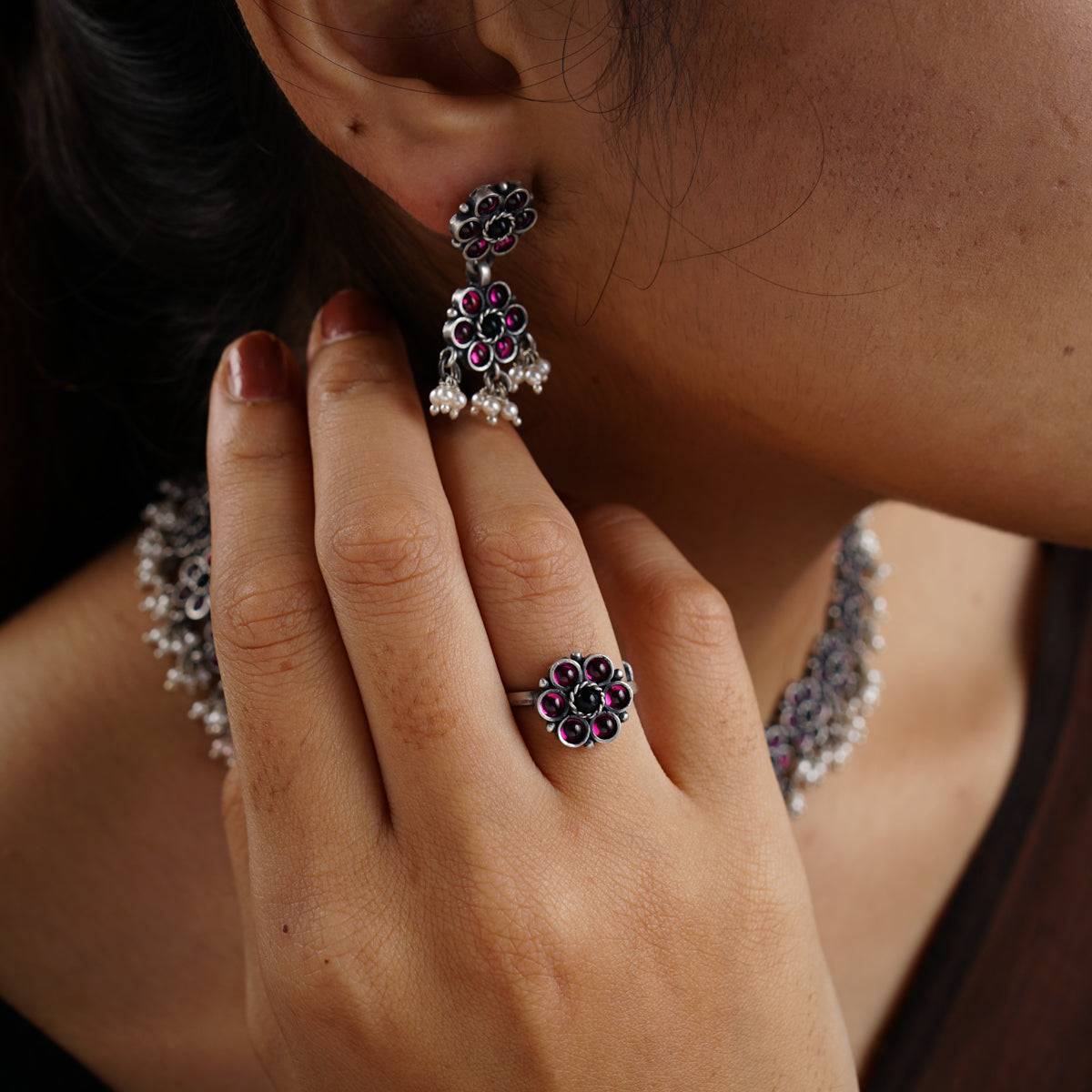 a close up of a person wearing a ring and earrings