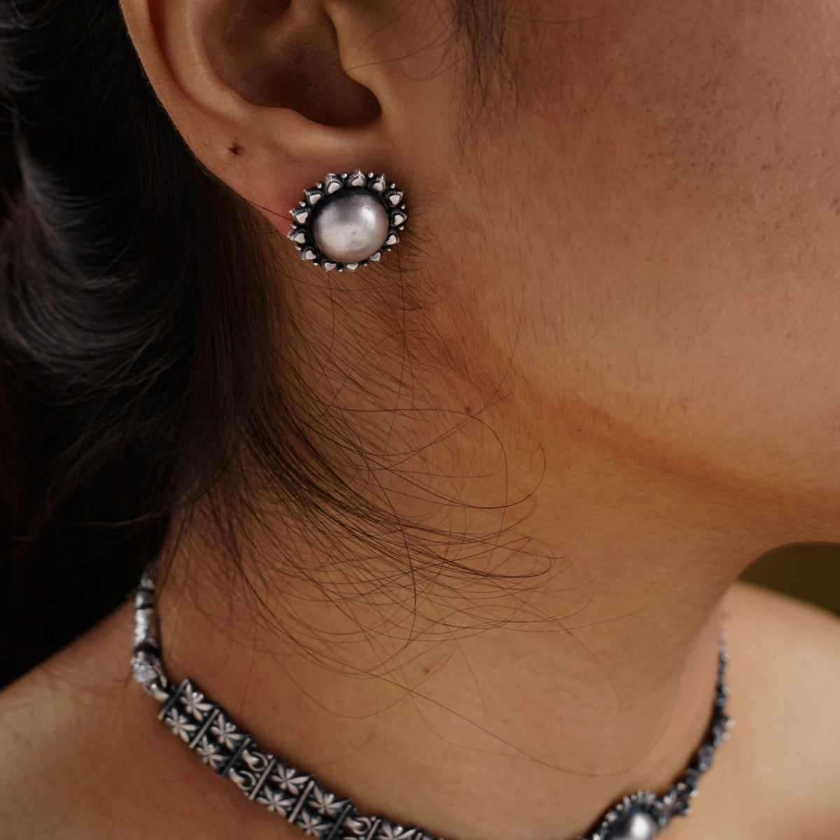 a close up of a person wearing a necklace and earrings