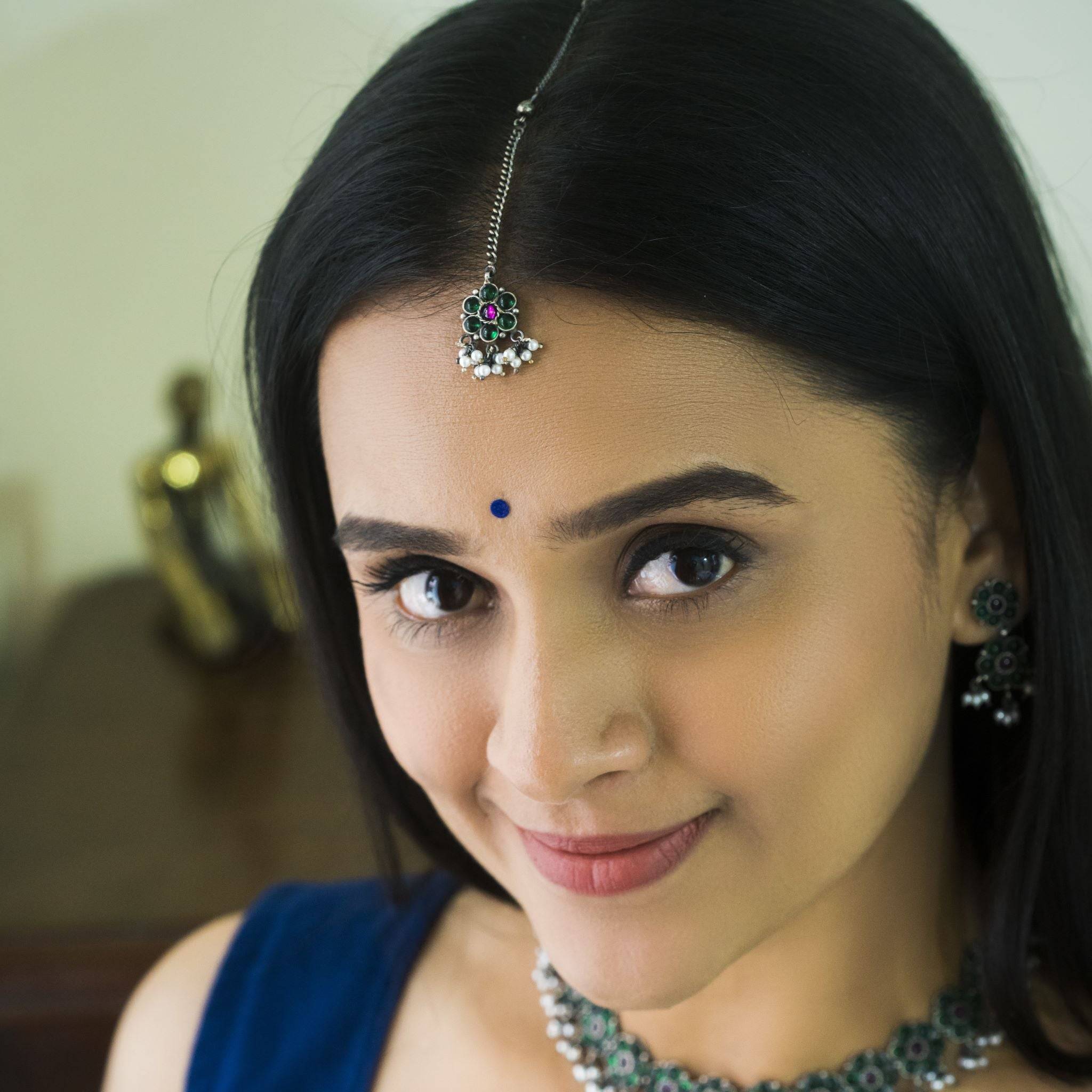 a woman in a blue dress wearing a necklace and earrings