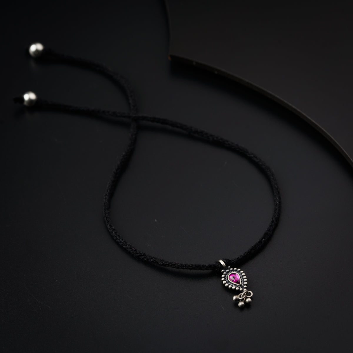 a black cord with a pink bead on it