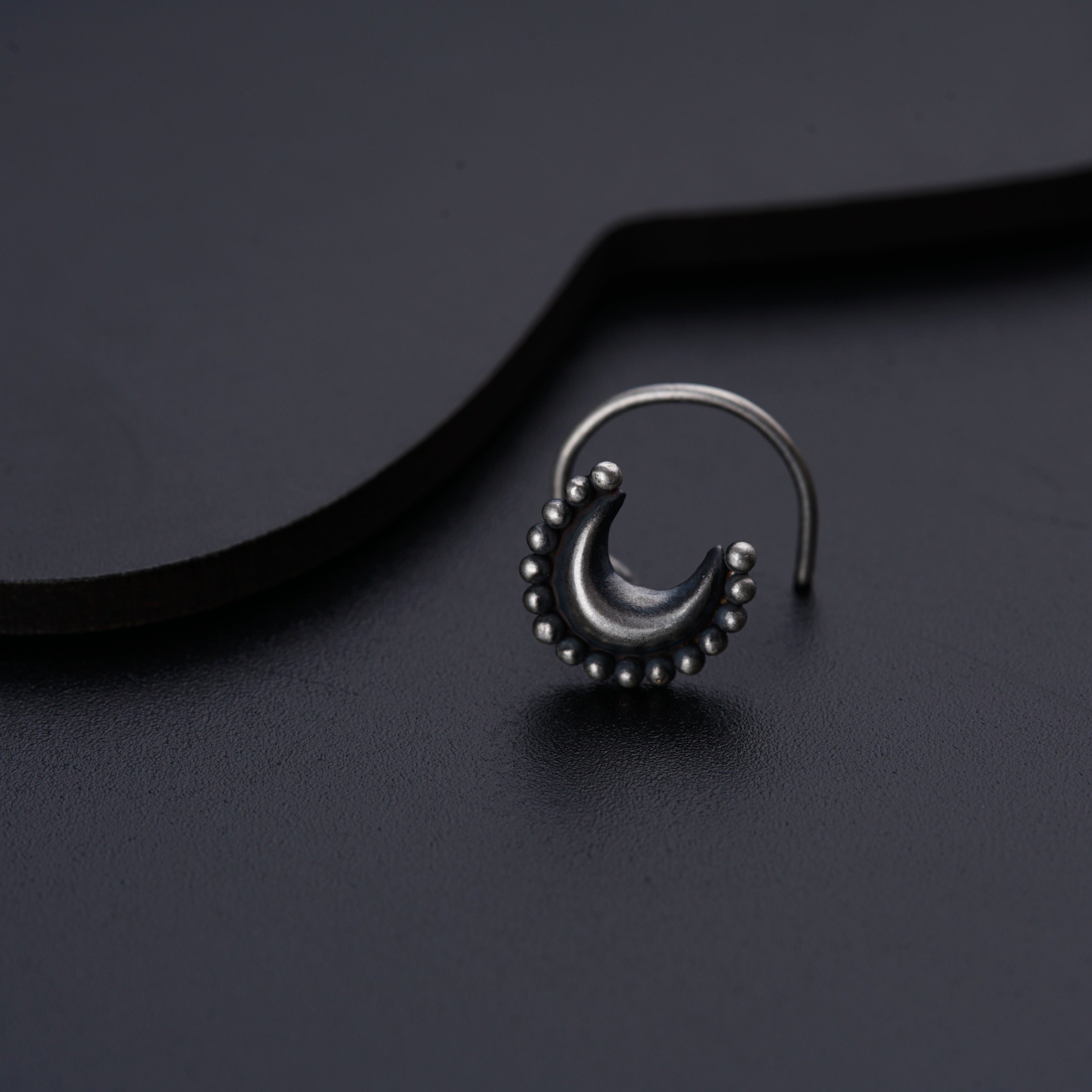 a pair of silver nose rings on a black surface