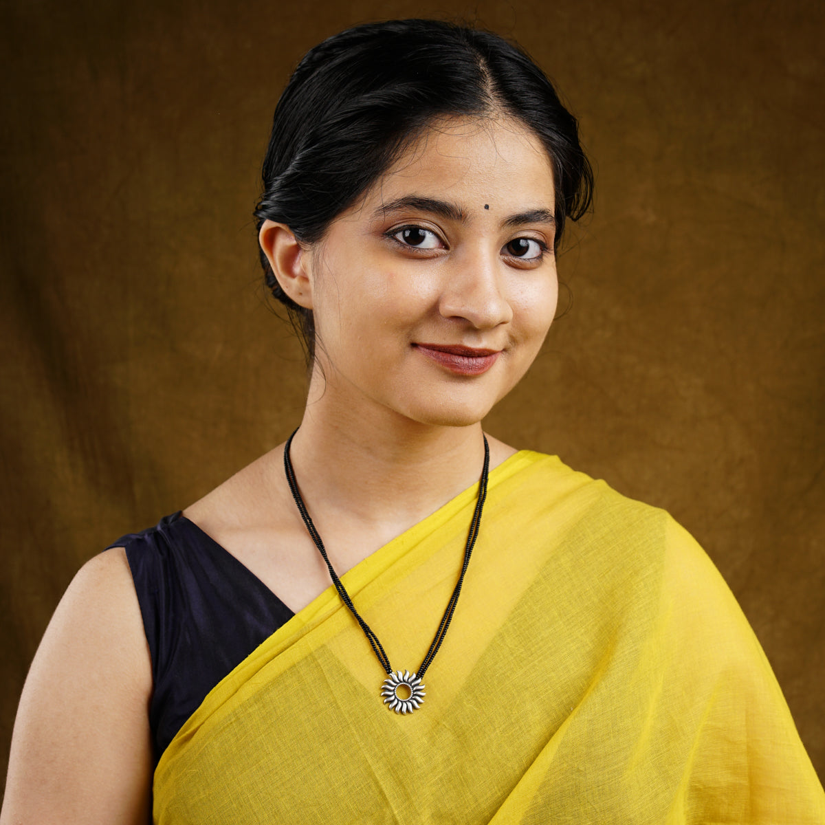 a woman wearing a yellow sari and a necklace