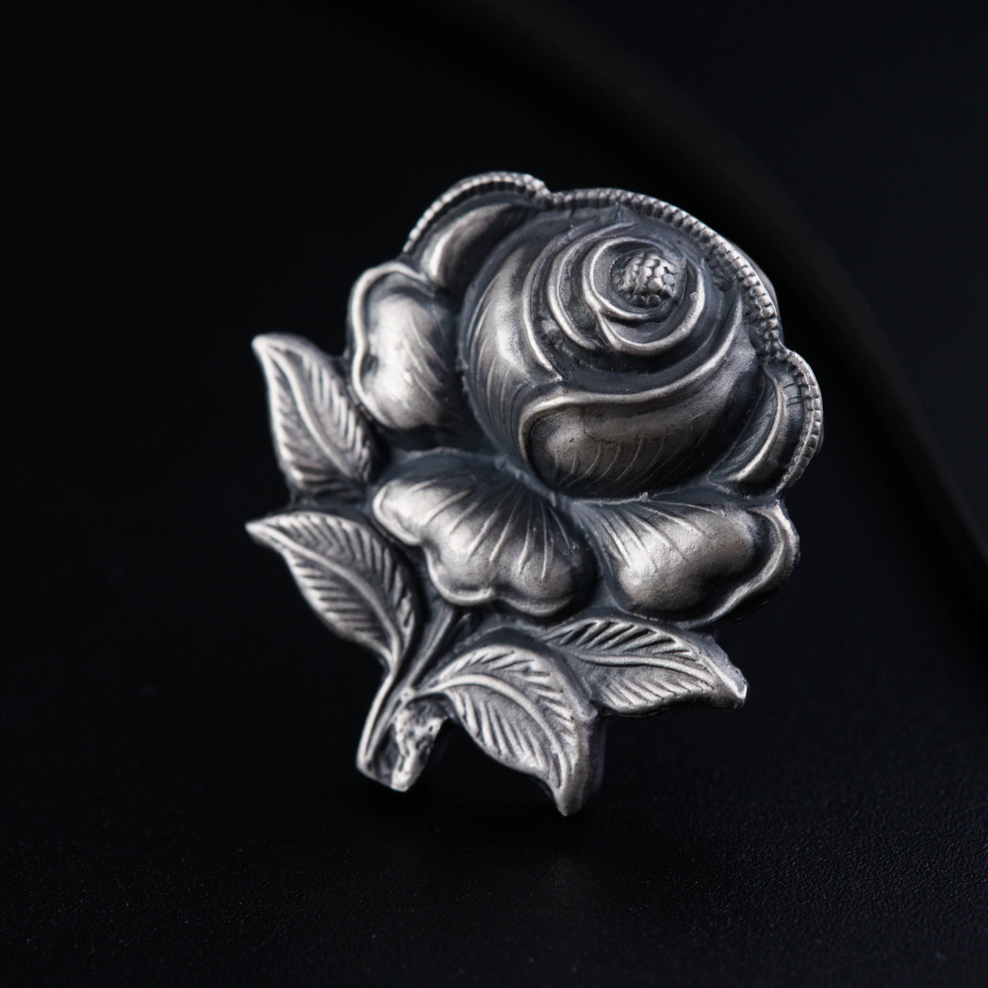 a silver rose ring sitting on top of a black surface