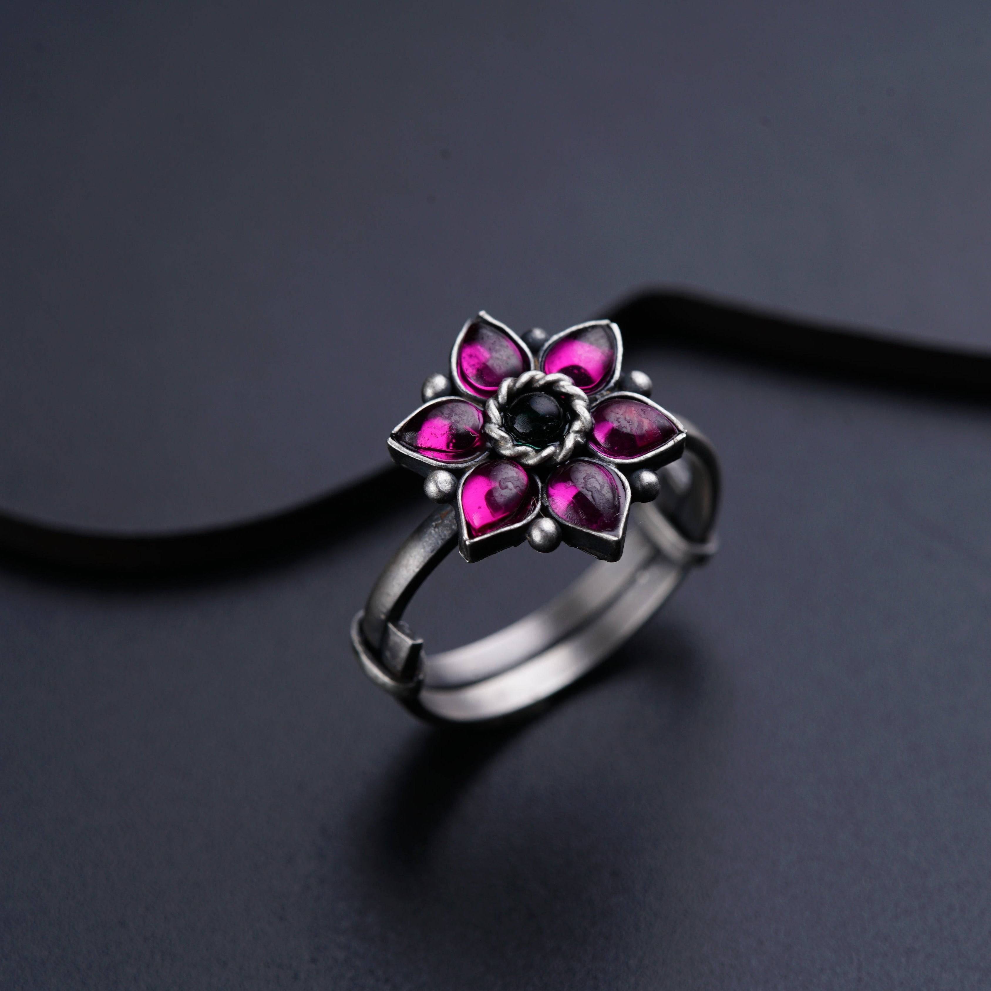 a silver ring with a pink flower on it