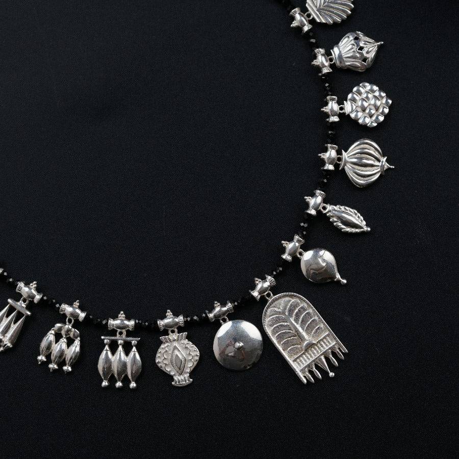 a silver necklace with silver charms on a black background