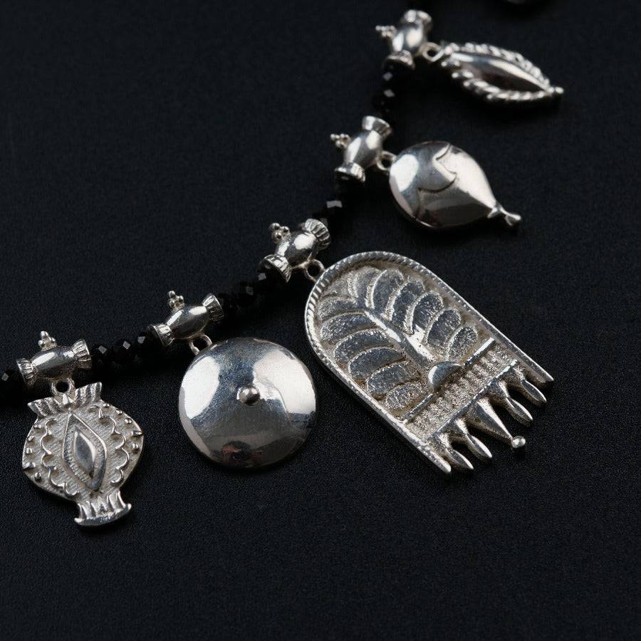 a black necklace with silver charms and a leaf