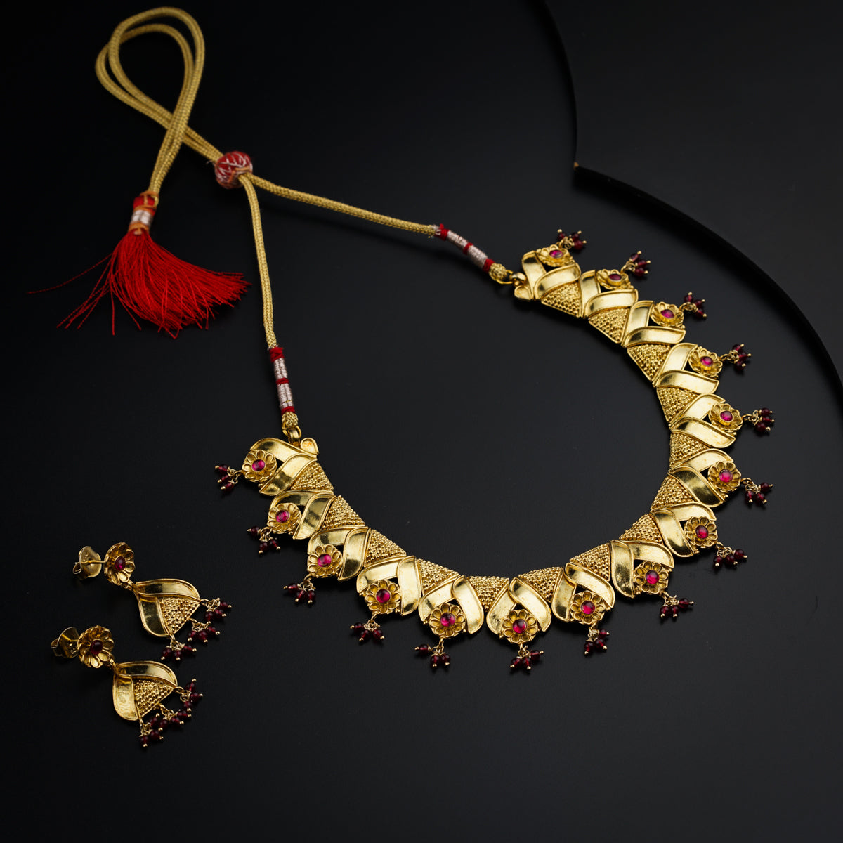 a gold necklace and matching earrings on a black surface