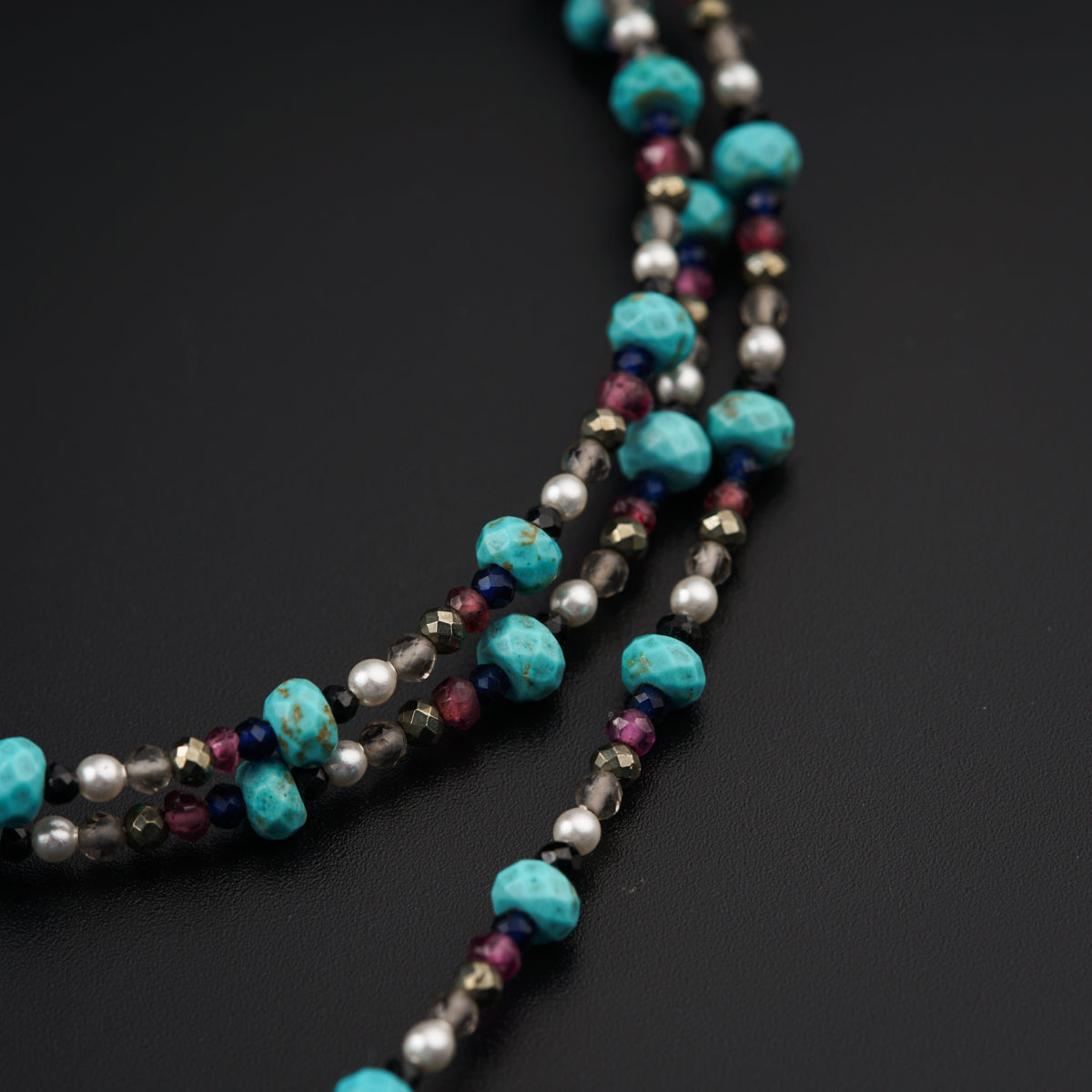 a multi strand of beaded necklace on a black surface