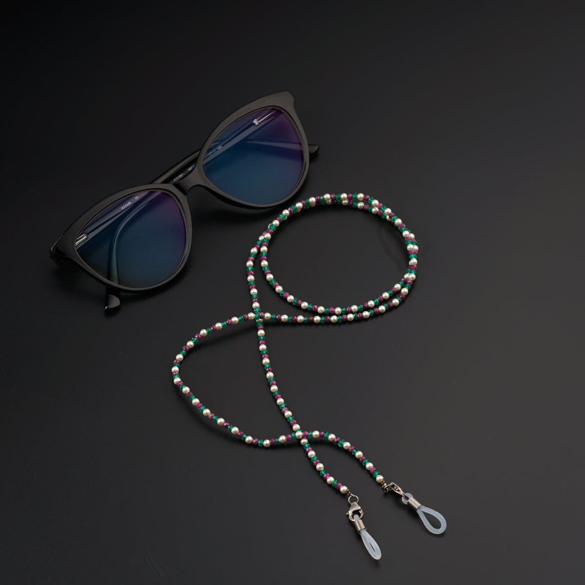 a pair of sunglasses and a beaded lanyard on a black surface