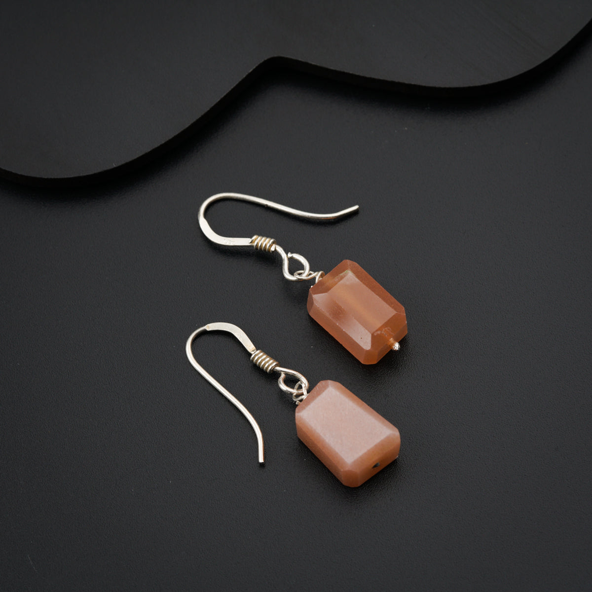 a pair of brown earrings on a black surface