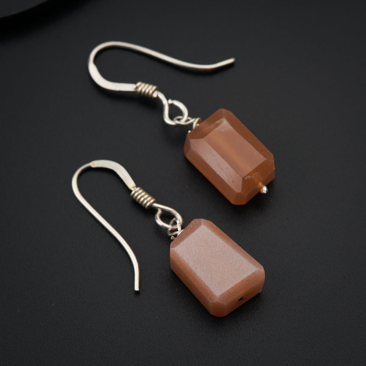 a pair of brown earrings on a black surface