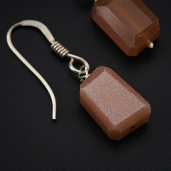 a pair of earrings with brown beads on a black background