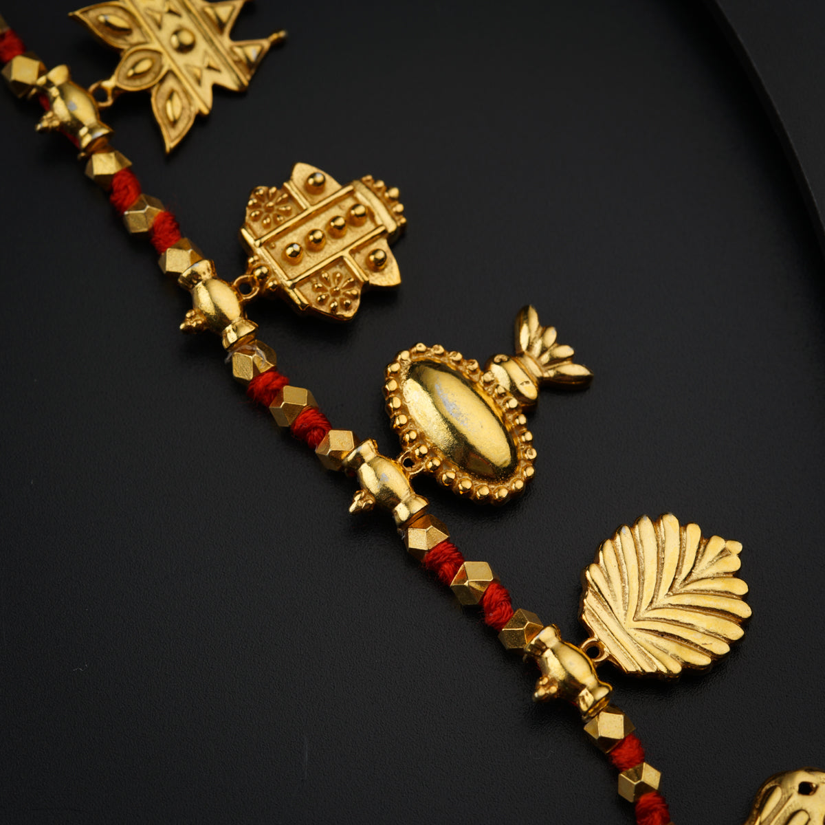 a close up of a gold necklace on a black surface