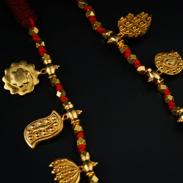 a close up of a gold necklace with red beads