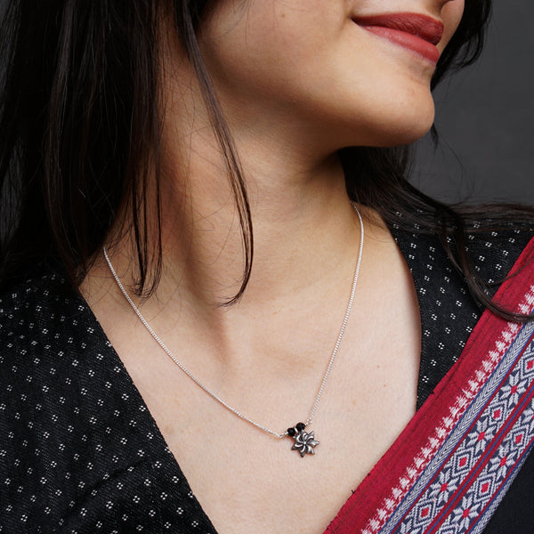 a woman wearing a necklace with a flower on it