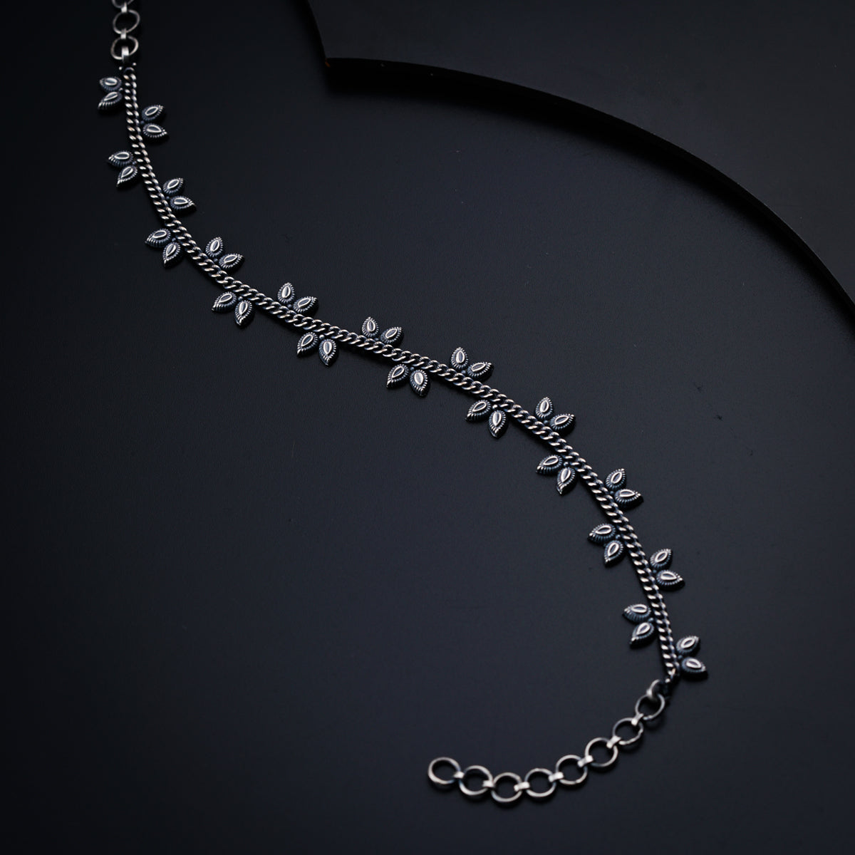 a silver necklace on a black background