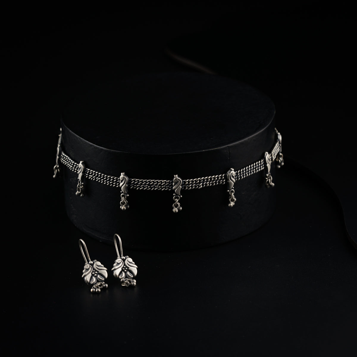 a choker and earring set on a black background