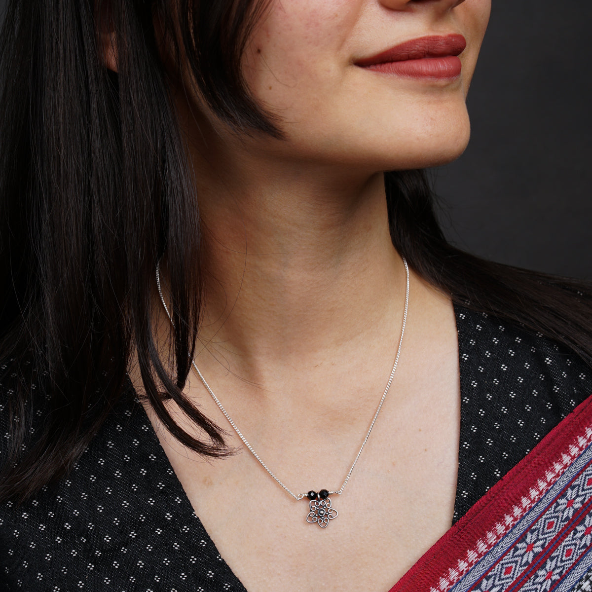 a woman wearing a necklace with a flower on it