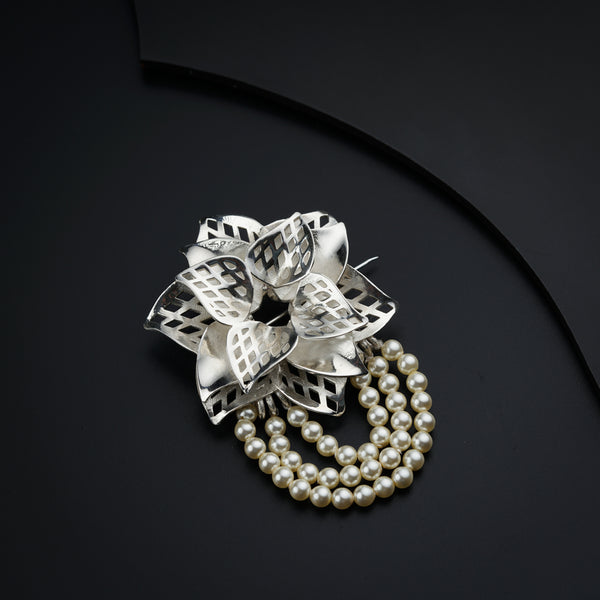a close up of a brooch with pearls
