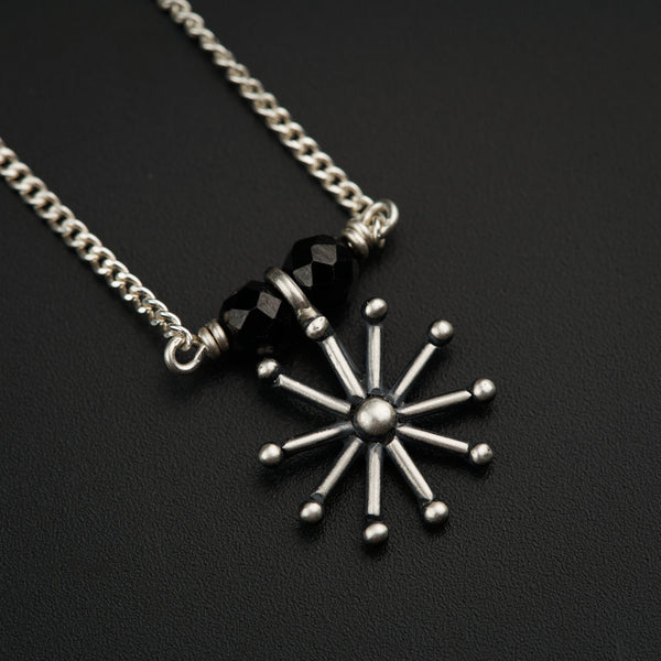 a black and white snowflake necklace on a black surface