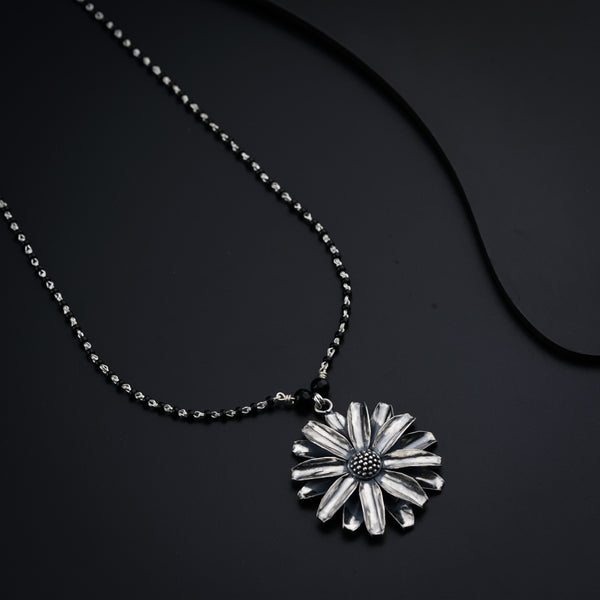 a necklace with a flower on a black background