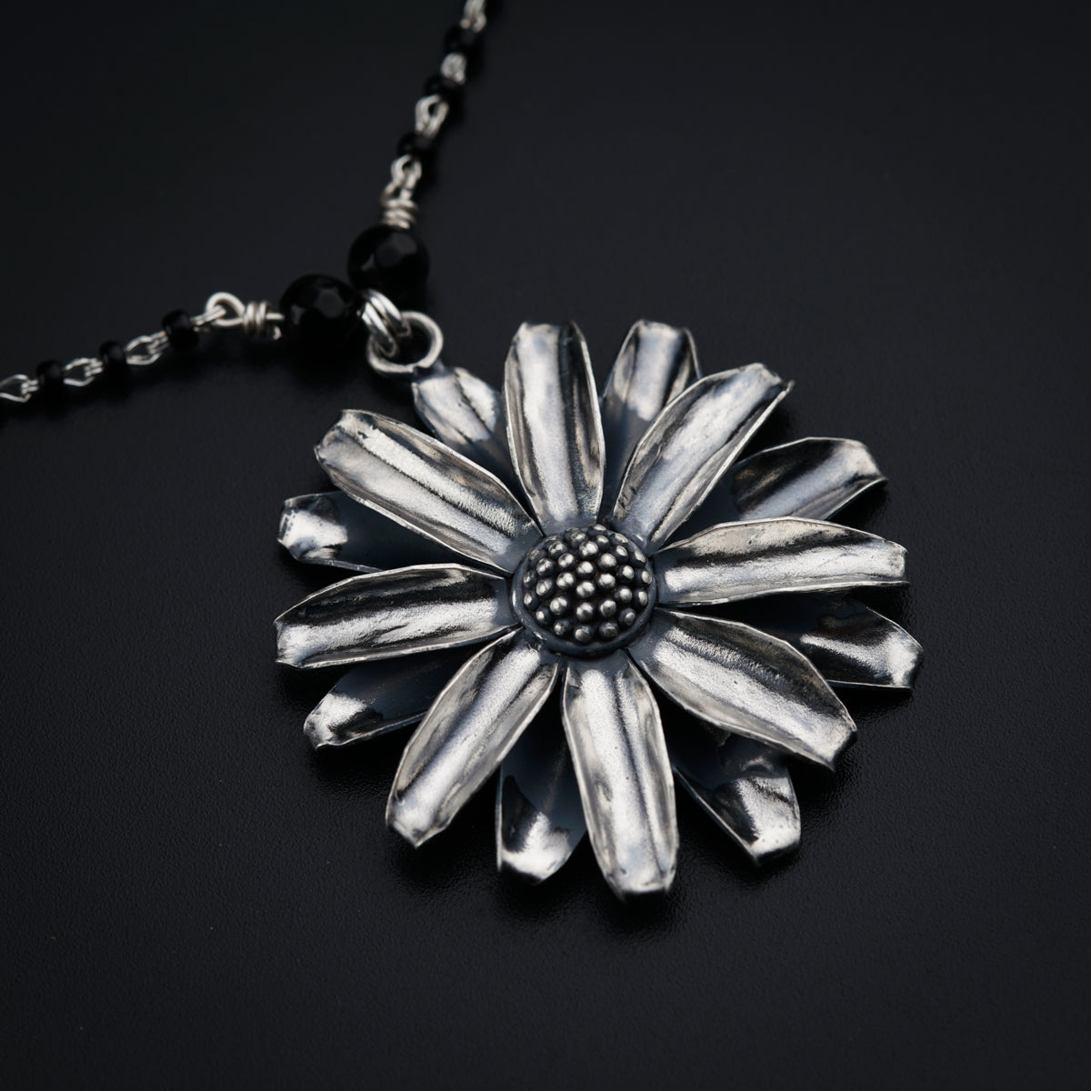 a silver flower pendant on a black background