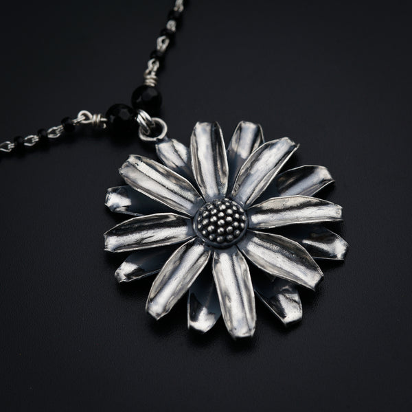 a silver flower pendant on a black background