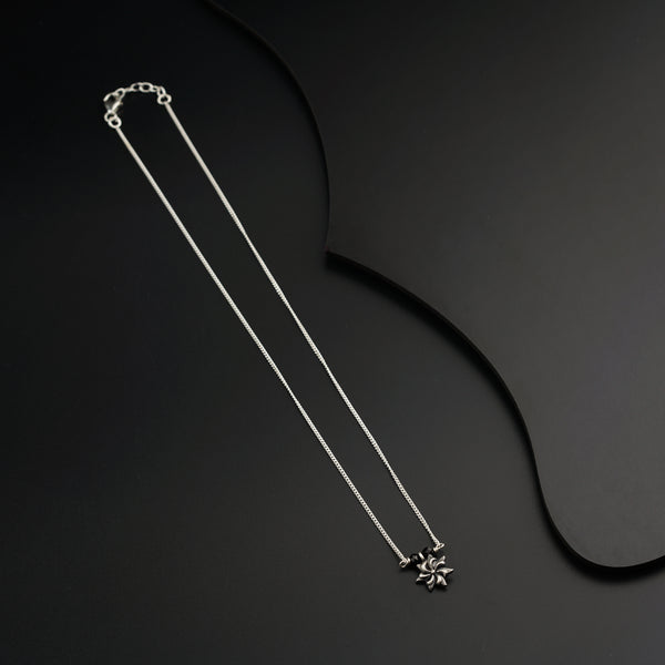 a silver necklace with a flower on a black background