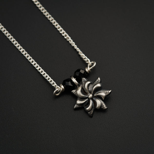 a black and silver necklace with a flower on it