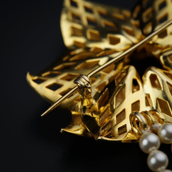 a close up of a brooch with pearls